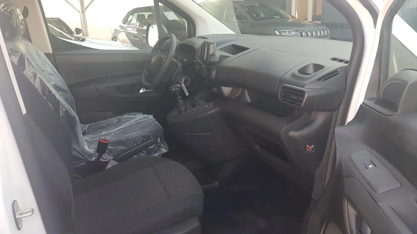 Vue intérieure côté conducteur du Citroën Berlingo blanc 2025, montrant le tableau de bord et la sellerie noire.