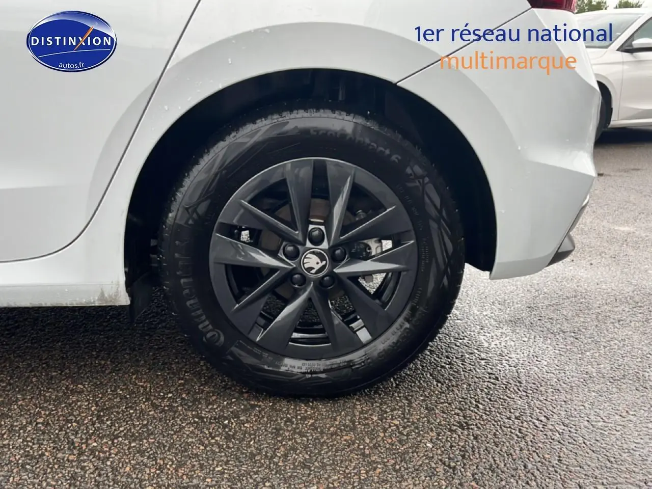 Gros plan sur la roue arrière gauche avec jante alu noire d'une Skoda Fabia blanche, vue de profil partiel.