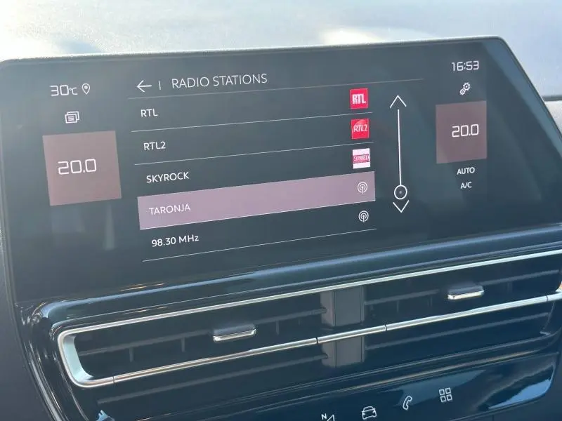Écran tactile central du tableau de bord du Citroën C5 Aircross noir, affichant les stations radio et la climatisation à 20°C.
