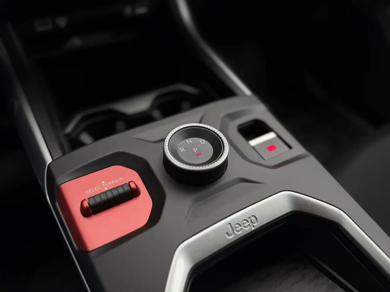 Gros plan sur la console centrale du Jeep Compass Hybrid 2026, avec molette de boîte auto et bouton Selec Terrain rouge.