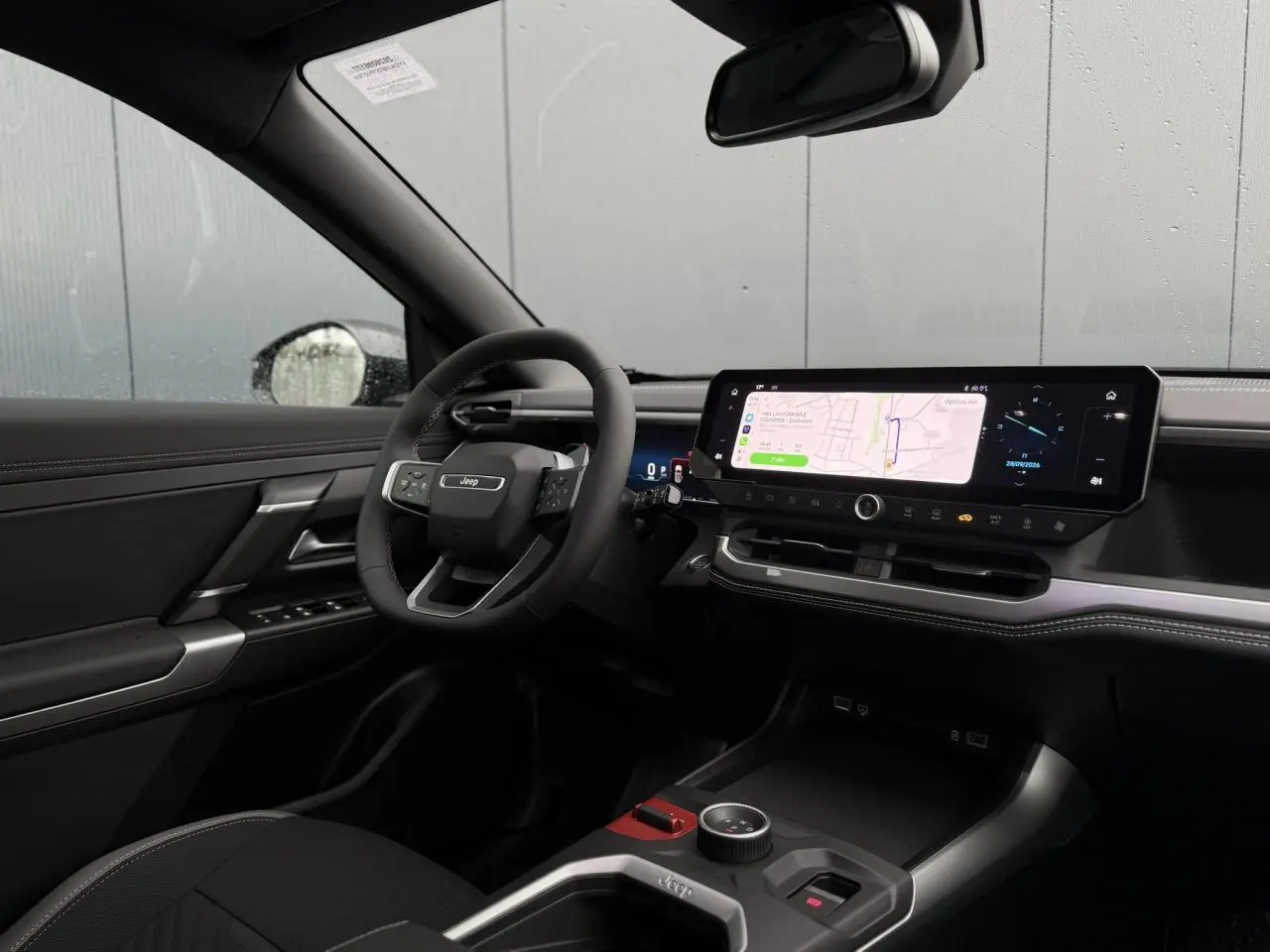 Intérieur noir du Jeep Compass Hybrid 2026 vu côté conducteur, avec grand écran tactile et volant multifonction.