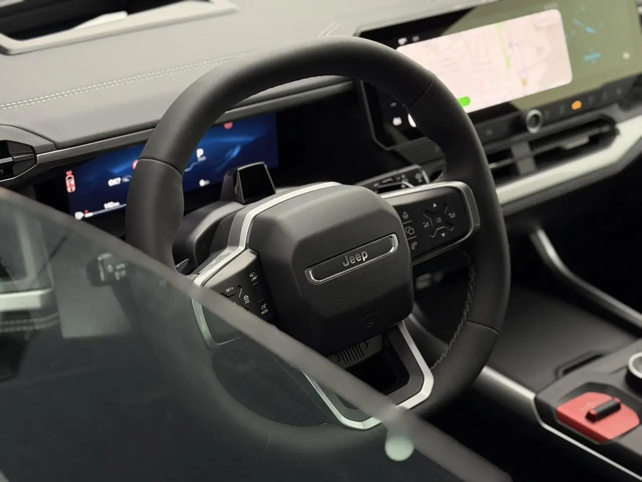 Vue rapprochée du volant noir du Jeep Compass 2026 avec tableau de bord numérique et écran tactile central.