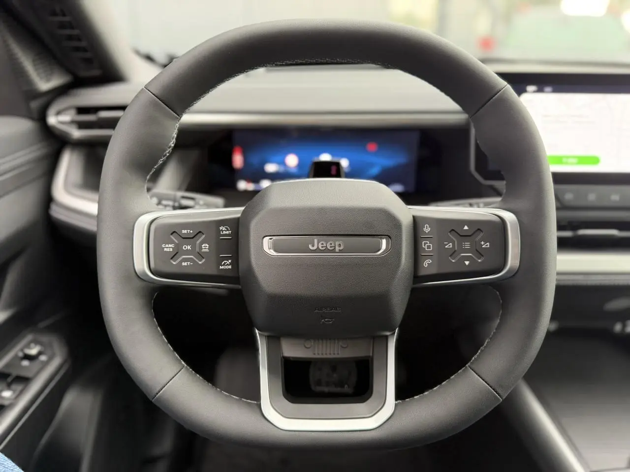 Vue frontale centrée sur le volant noir du Jeep Compass 2026 avec commandes intégrées et tableau de bord numérique.