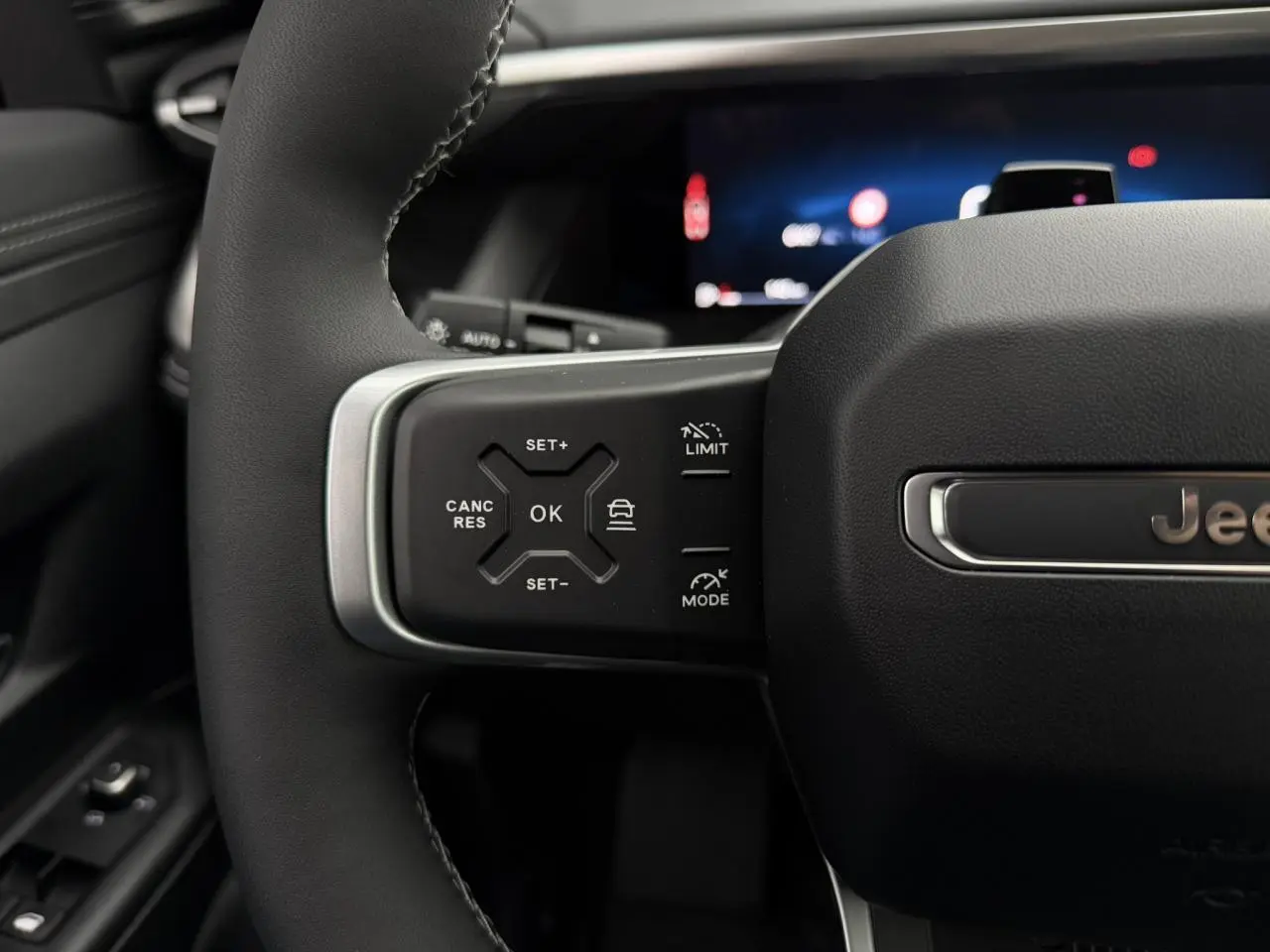 Gros plan sur le volant noir du Jeep Compass 2026, mettant en valeur les commandes du régulateur adaptatif côté gauche.