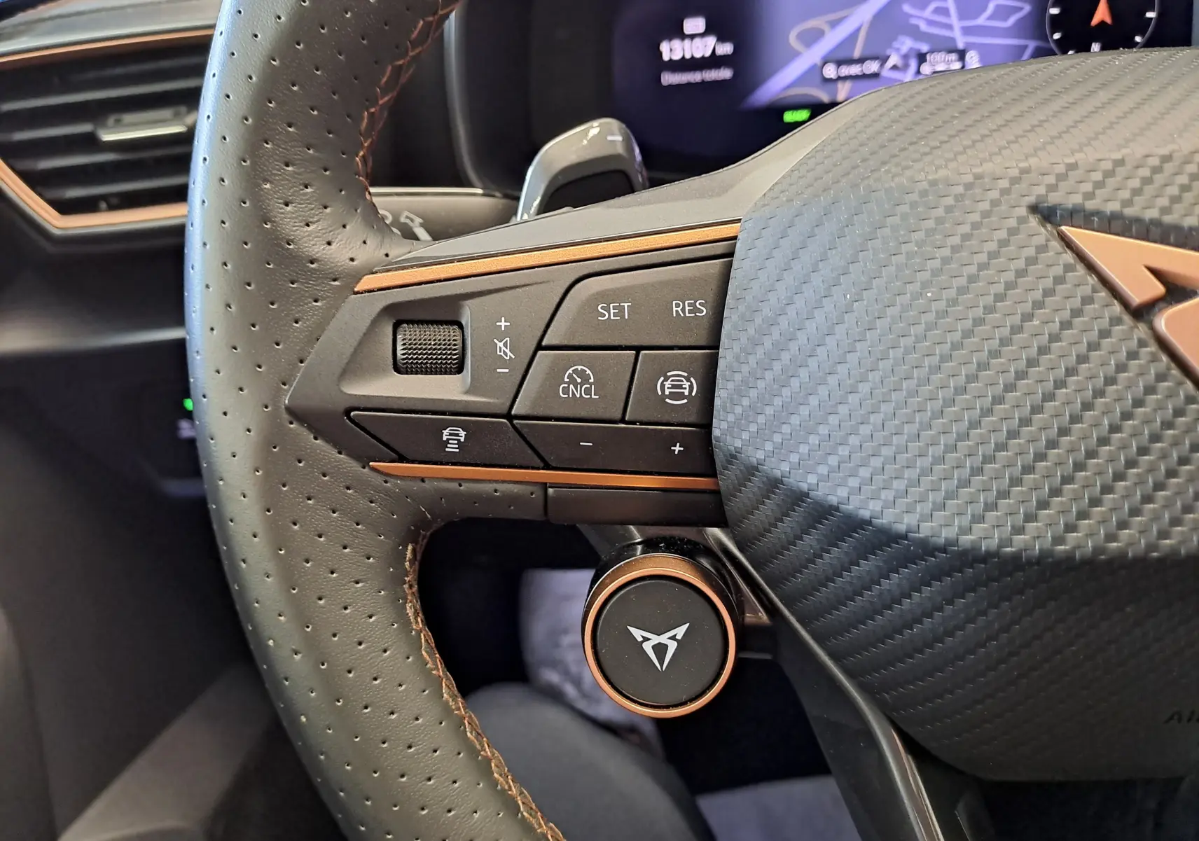 Gros plan sur le volant perforé noir avec surpiqûres cuivrées et commandes intégrées du CUPRA LEON ST 1.5 eTSI 2025.