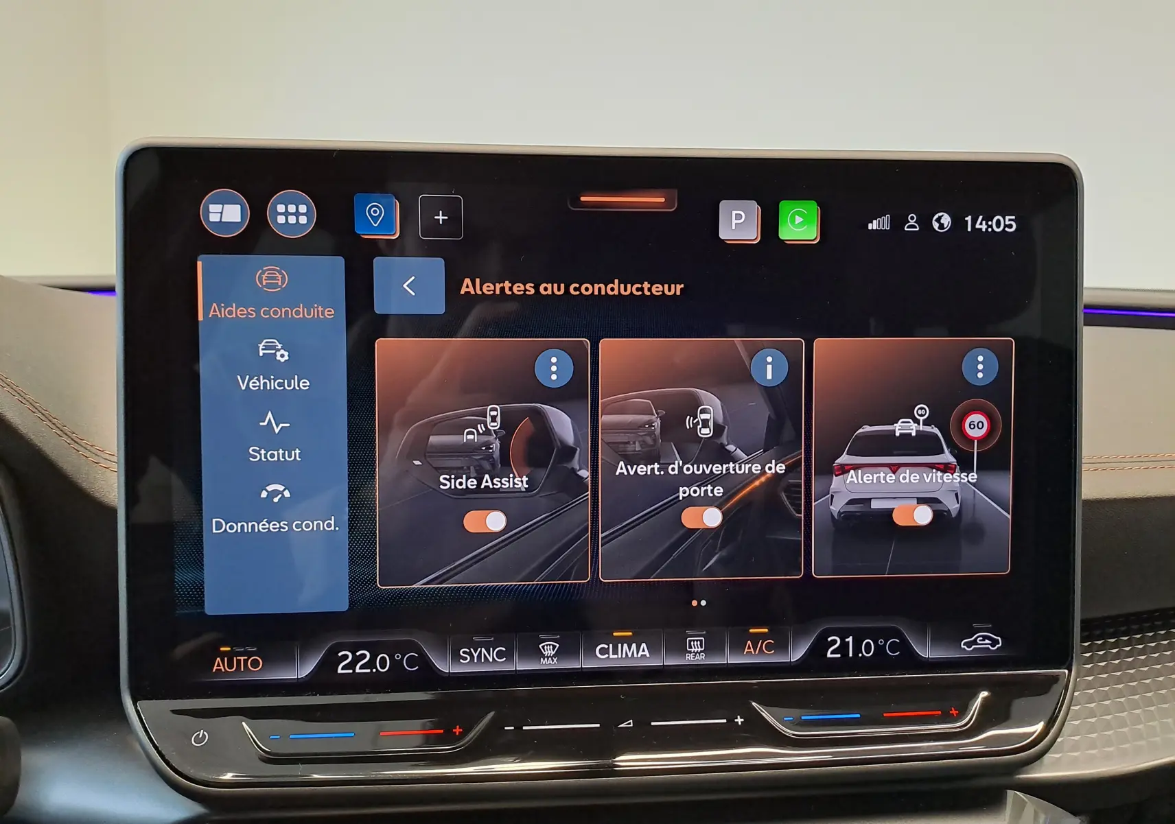 Écran tactile intérieur affichant les aides à la conduite du CUPRA LEON ST 1.5 eTSI, avec commandes climatisation en bas.