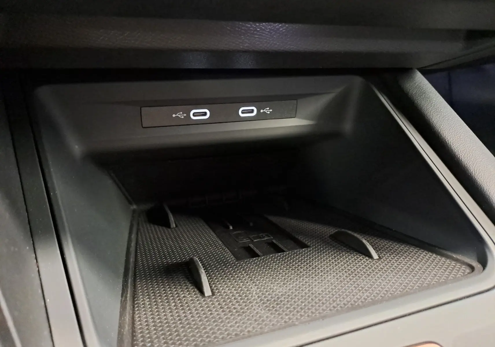 Gros plan sur la zone de rangement avant avec deux ports USB-C lumineux dans l’habitacle noir du CUPRA LEON ST 2025.