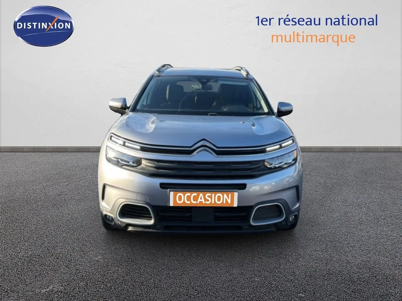 Vue frontale d'un Citroën C5 Aircross gris Artense métal avec calandre distinctive et phares LED allumés.