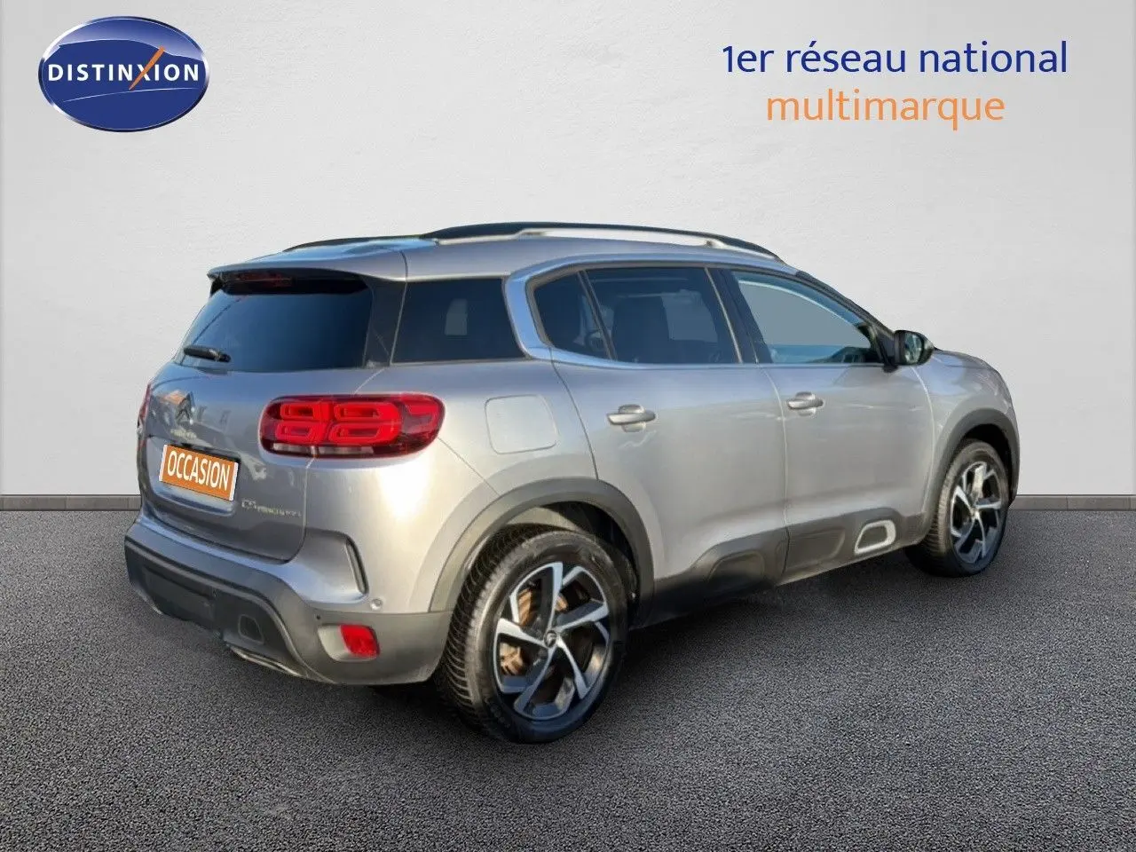 Vue 3/4 arrière droite d'un Citroën C5 Aircross gris Artense métal avec feux arrière LED et jantes bicolores.