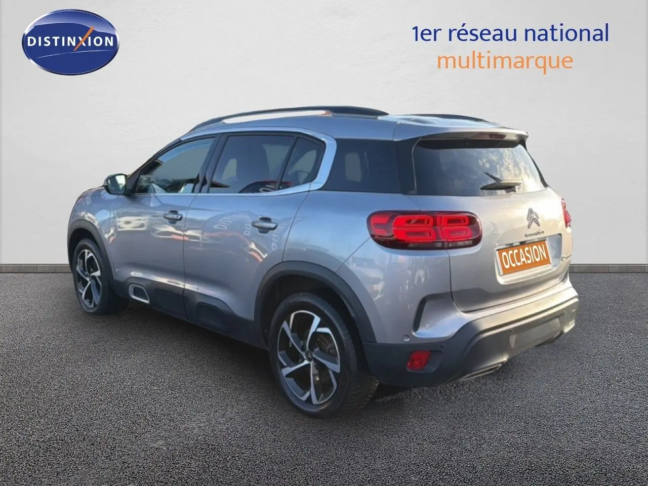 Vue 3/4 arrière droite d'un Citroën C5 Aircross gris Artense métallisé avec jantes bi-ton et feux LED distinctifs.