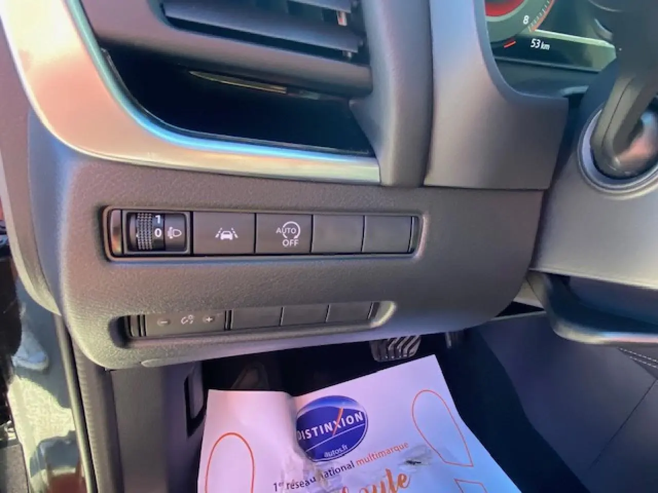 Détail des commandes d'aide à la conduite sous le tableau de bord côté gauche du Nissan Qashqai noir 2023.