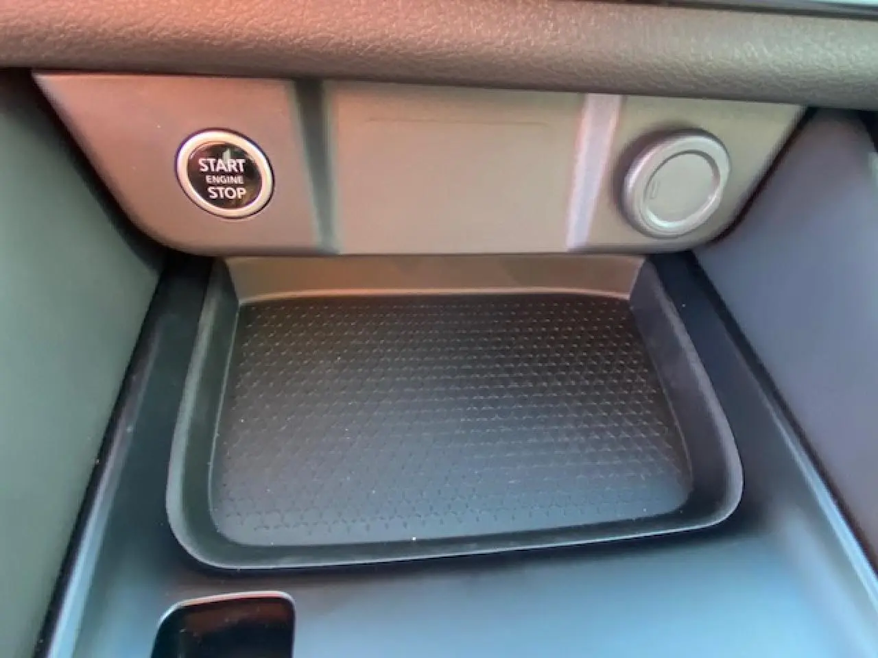 Détail de la console centrale du Nissan Qashqai 2023 noir avec bouton start/stop et espace de rangement texturé.