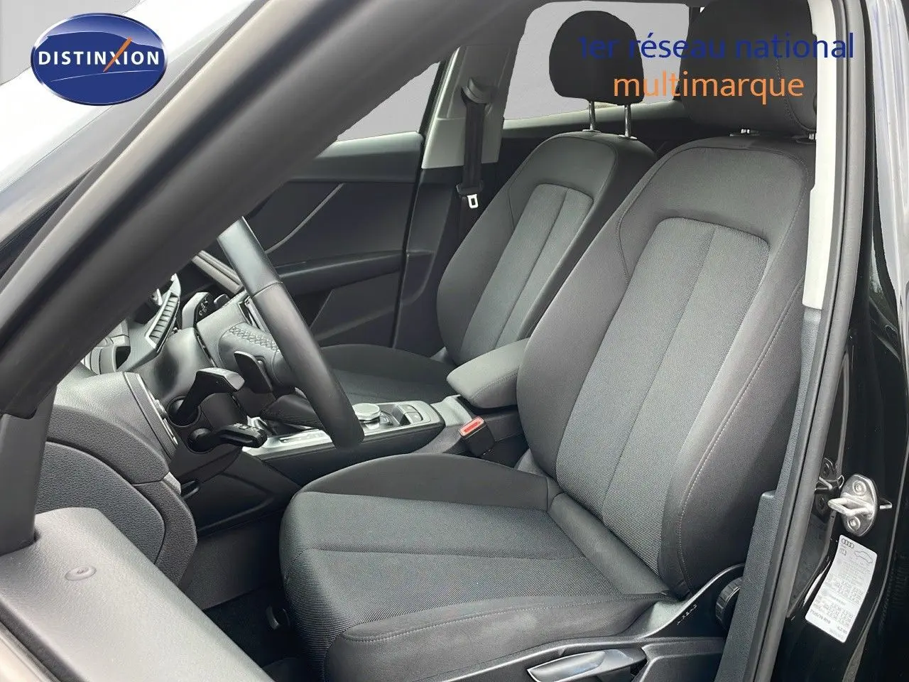 Intérieur noir de l'Audi Q2 35 TFSI 2023 vu côté gauche, avec sièges tissu et volant multifonction.