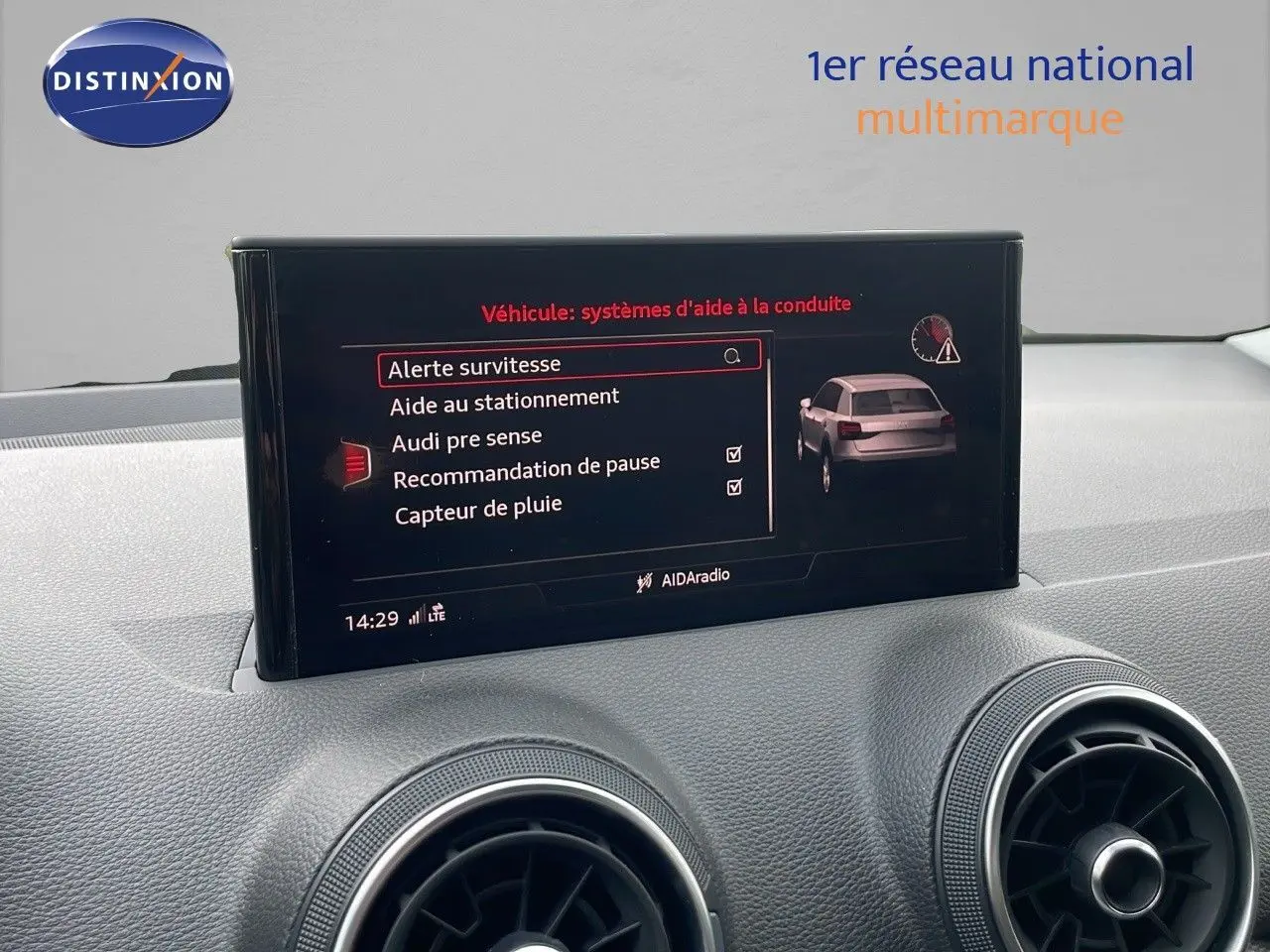 Écran central affichant les aides à la conduite dans l'habitacle d'un Audi Q2 2023, tableau de bord gris.