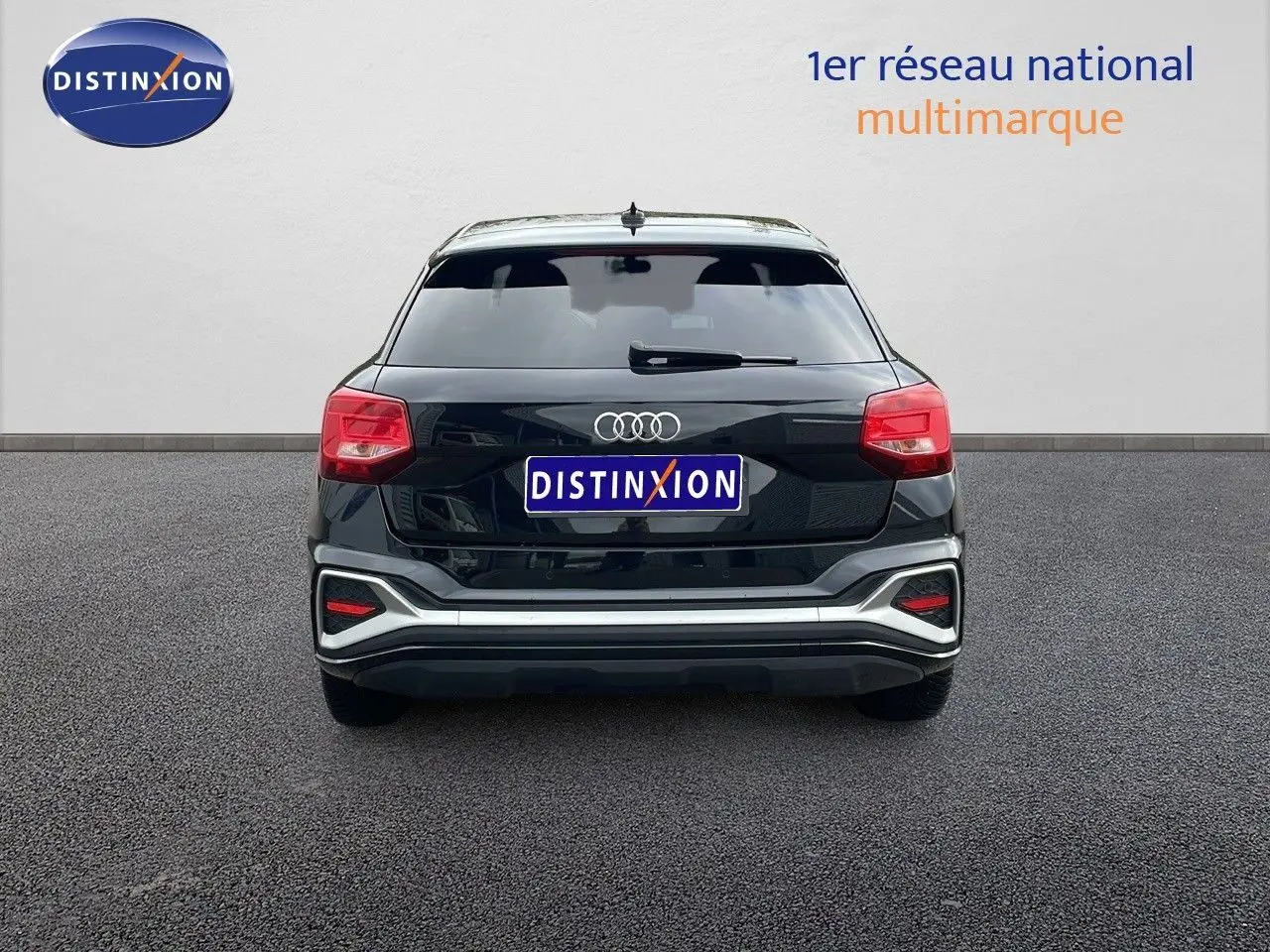 Vue arrière d'un Audi Q2 noir mito metal 2023 avec feux arrière rouges et logo quatre anneaux bien visible.