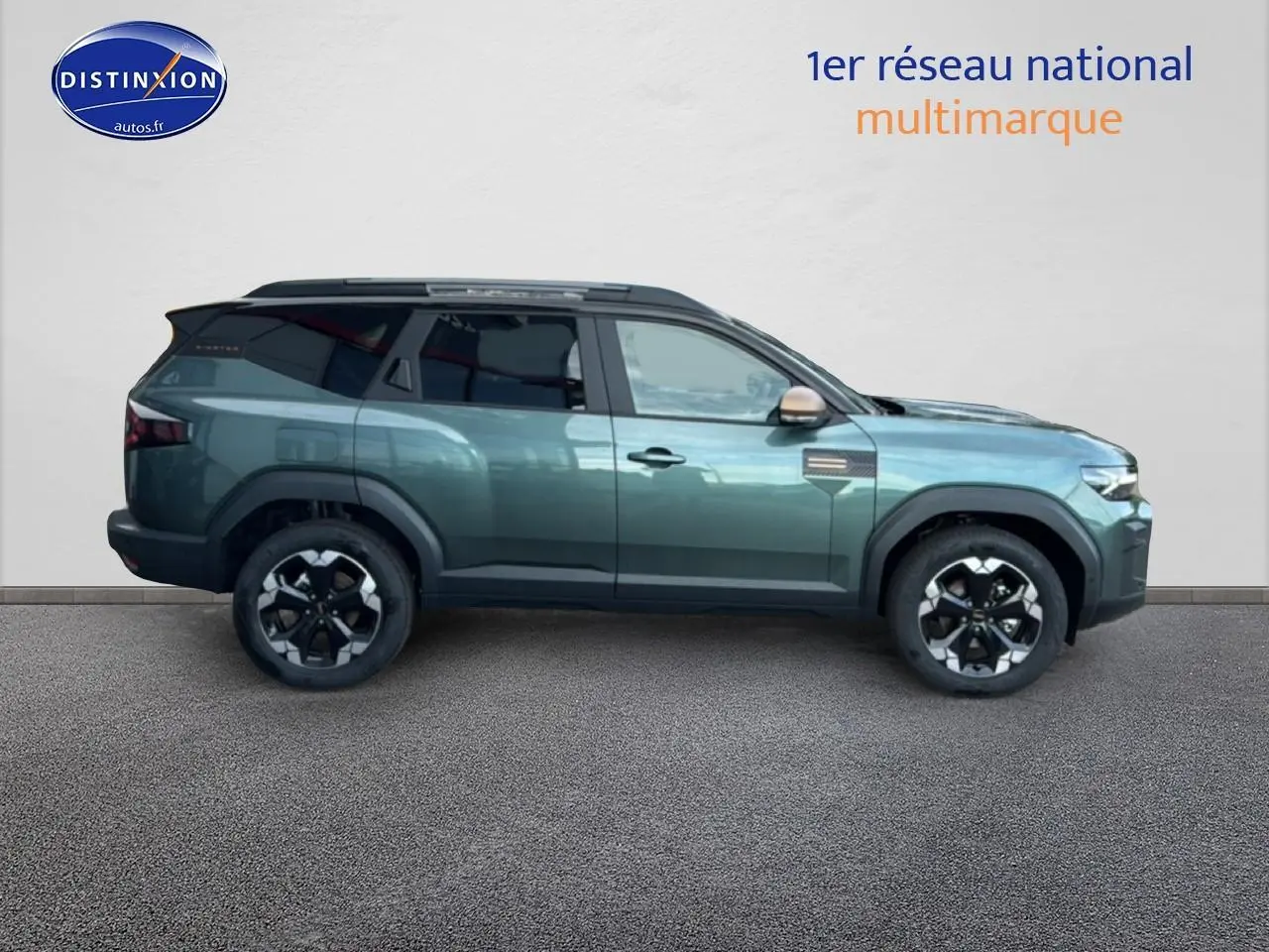 Vue latérale droite du Dacia Bigster 2025 vert cèdre avec jantes noires et barres de toit noires.