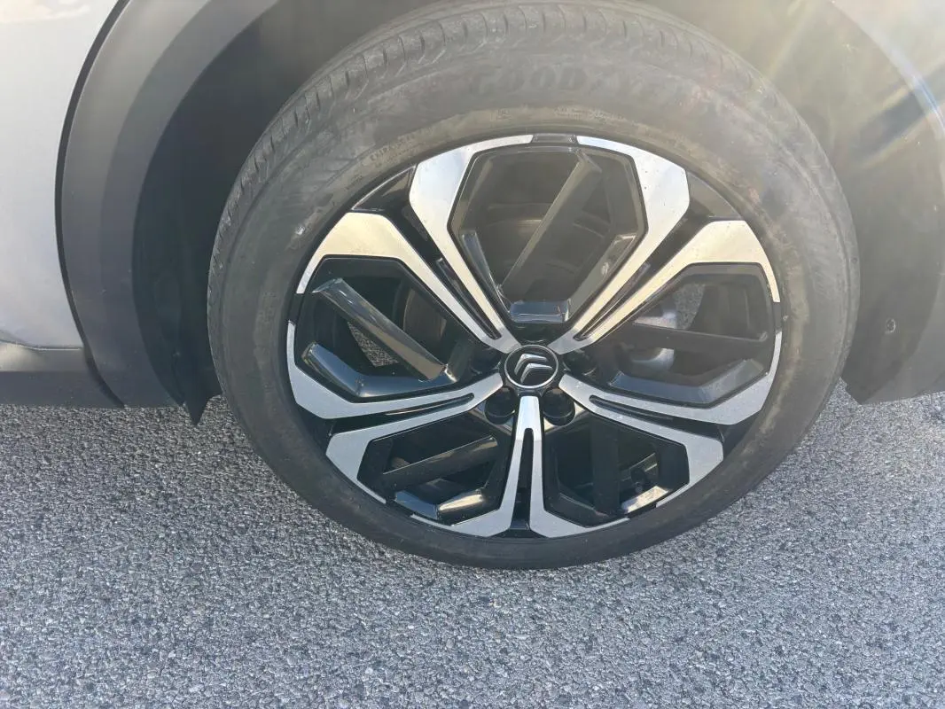 Gros plan sur la jante alliage 19 pouces noire et argentée d'une Citroën C5 X gris foncé, côté avant droit.