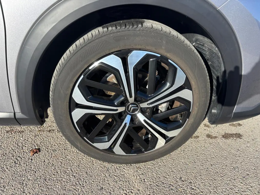 Gros plan sur la jante alliage 19 pouces noire et argentée du côté avant droit du Citroën C5 X gris foncé 2024.