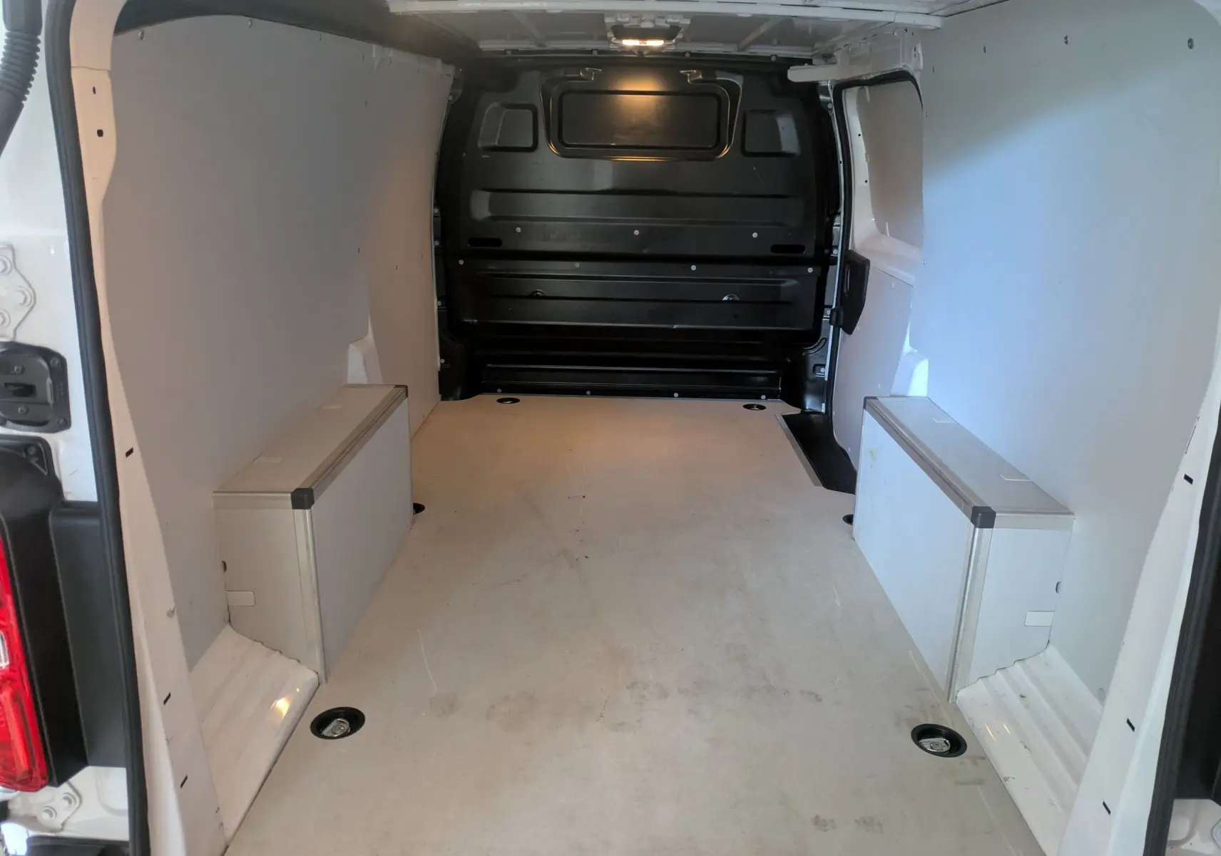 Vue intérieure arrière du fourgon Opel Vivaro XL blanc, montrant l'espace de chargement protégé par des panneaux en bois.