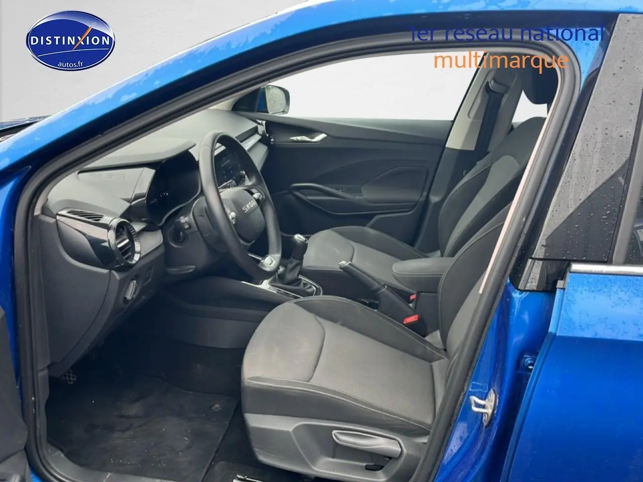 Intérieur avant droit de la Skoda Fabia bleu 2025, montrant sièges noirs, volant cuir multifonction et levier de vitesse manuel.
