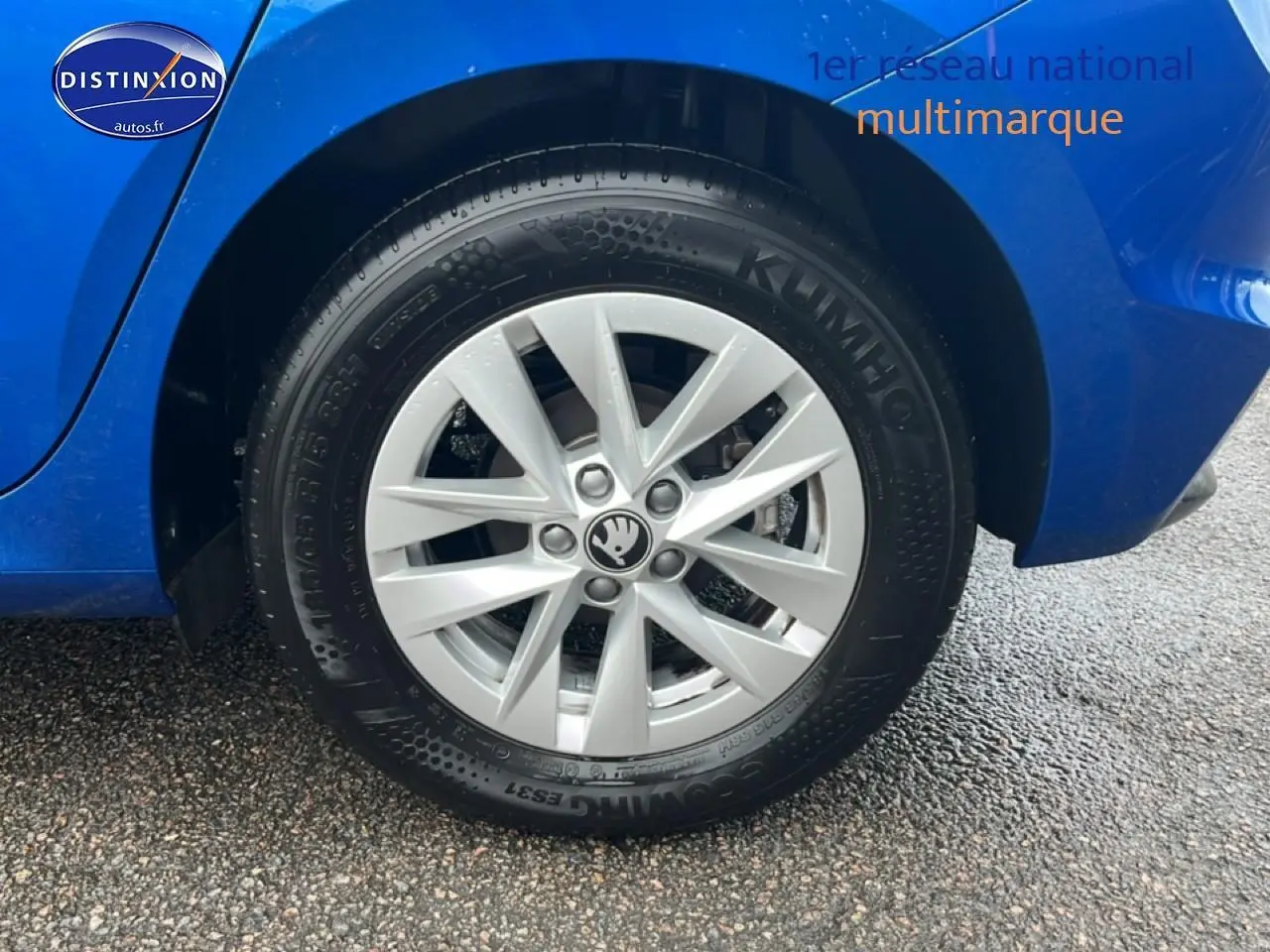 Gros plan sur la roue arrière droite d'une Skoda Fabia bleu 2025 avec jante alu et logo Skoda au centre.