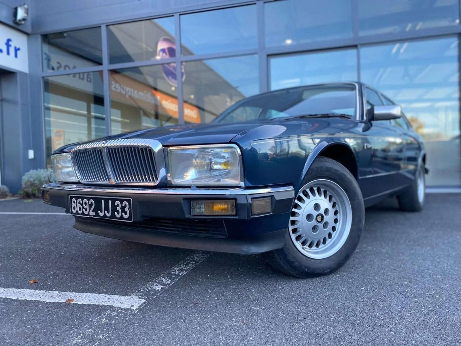 Jaguar XJ6 3.6 Sovereign bleu vue 3/4 avant mettant en valeur sa calandre chromée et ses jantes d'origine.