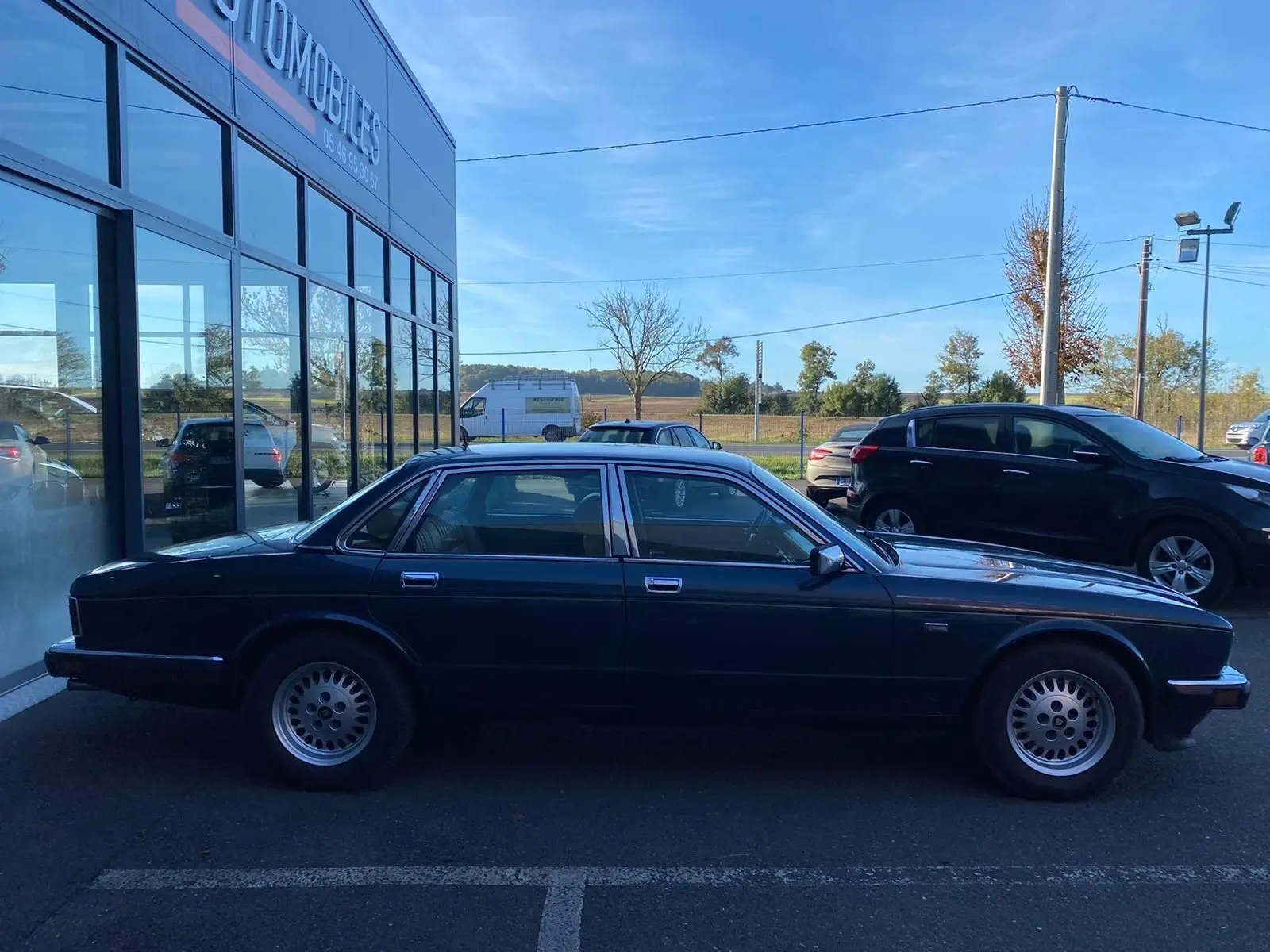 Profil côté droit d'une Jaguar XJ6 3.6 Sovereign bleu foncé de 1987, élégante berline classique aux jantes d'origine.