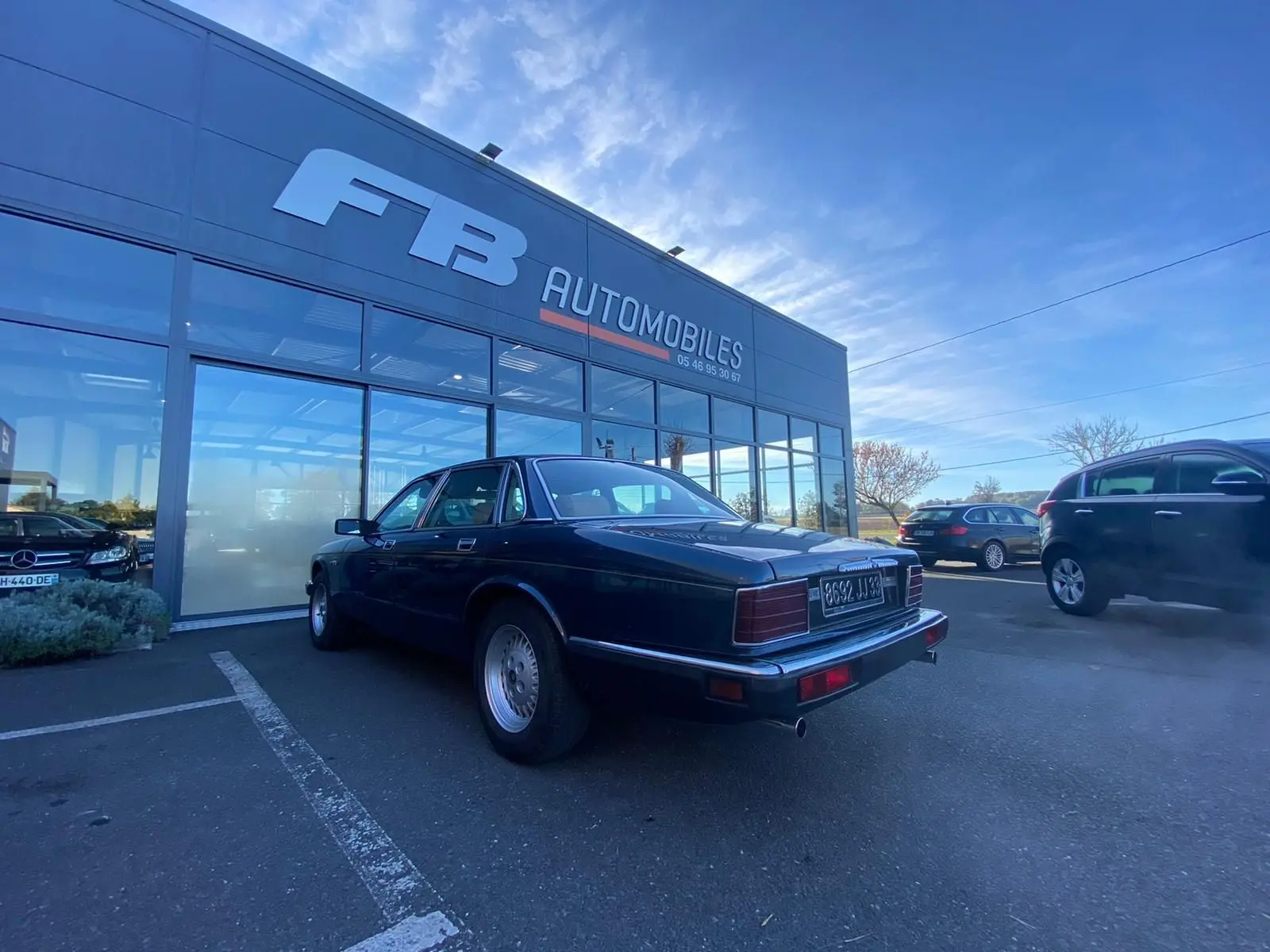Jaguar XJ6 3.6 Sovereign bleu vue 3/4 arrière droit, stationnée devant un garage avec plaques françaises.