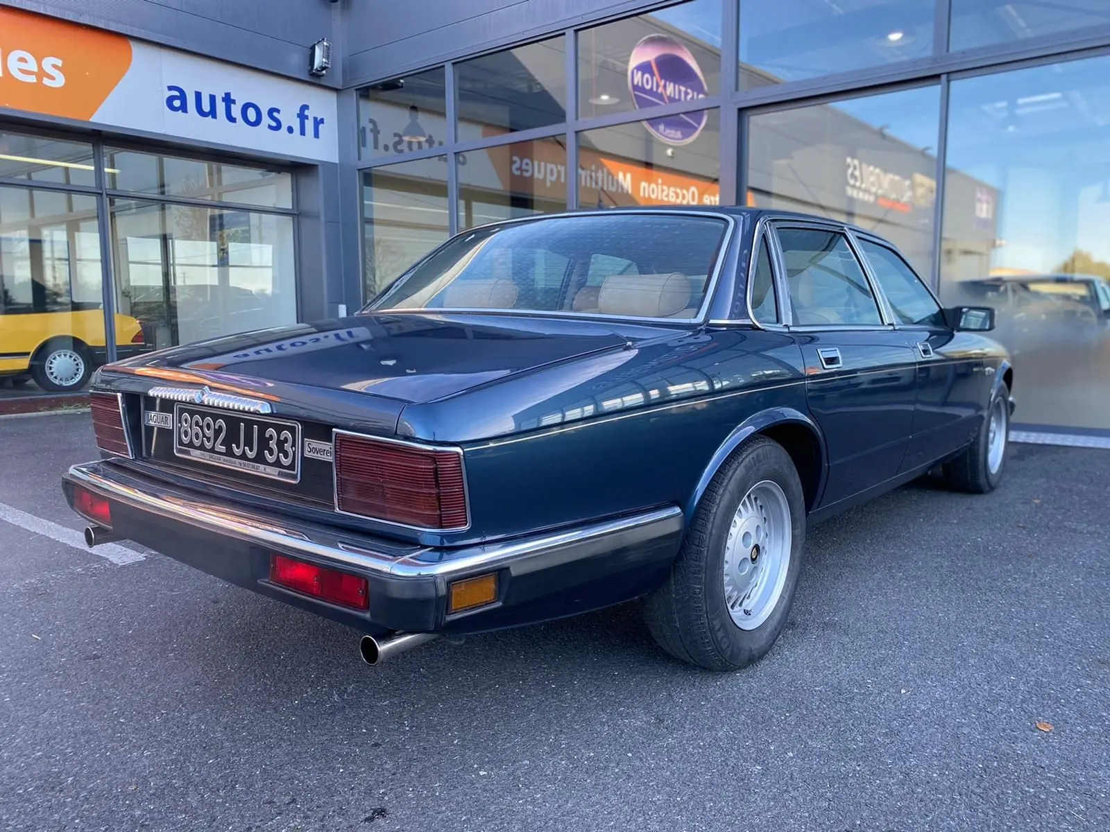 Vue 3/4 arrière droite d'une Jaguar XJ6 3.6 Sovereign bleu foncé de 1987 avec plaques françaises et jantes alliage.