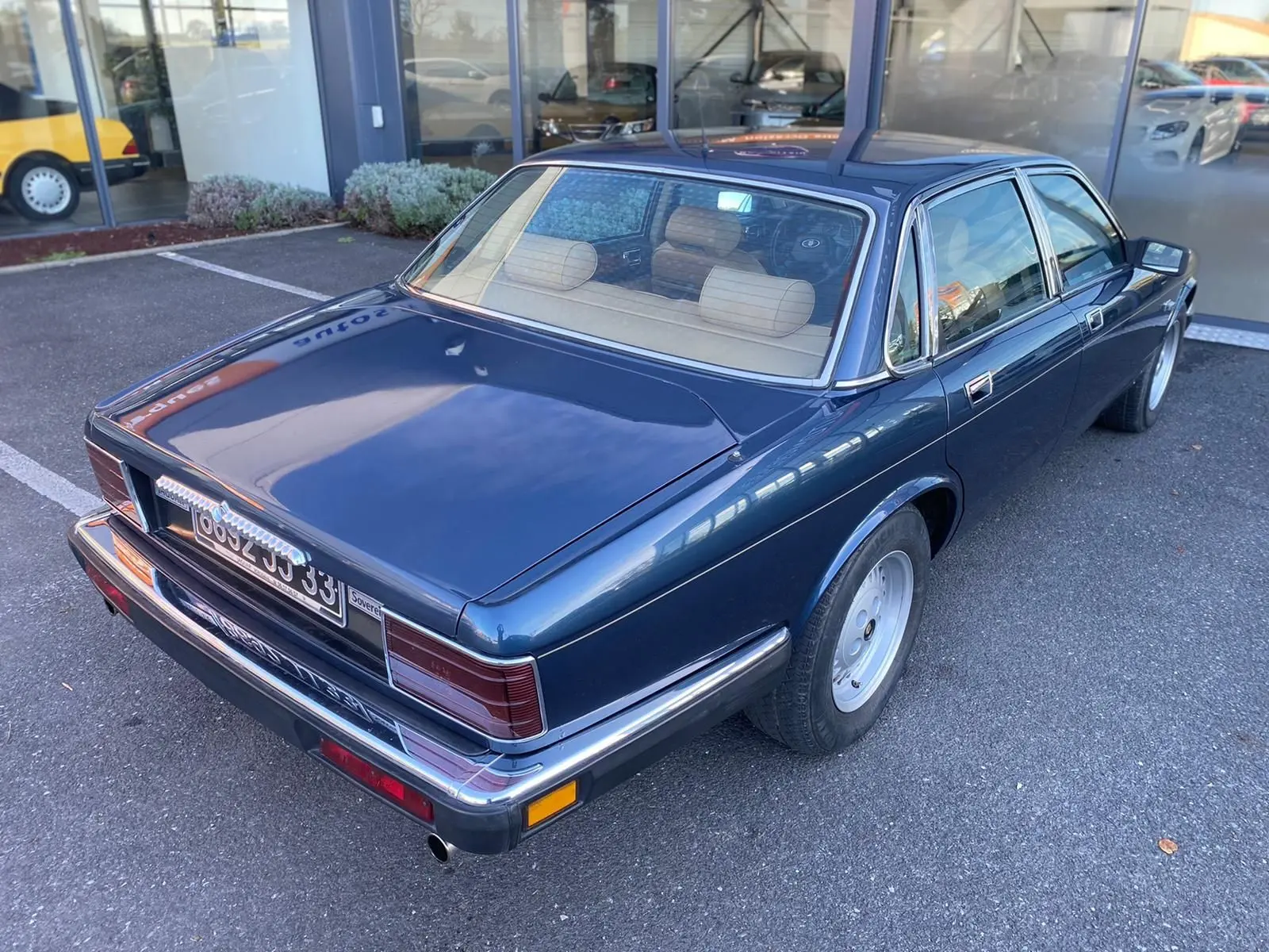 Vue 3/4 arrière droite d'une Jaguar XJ6 3.6 Sovereign bleu 1987 avec intérieur beige et jantes classiques.