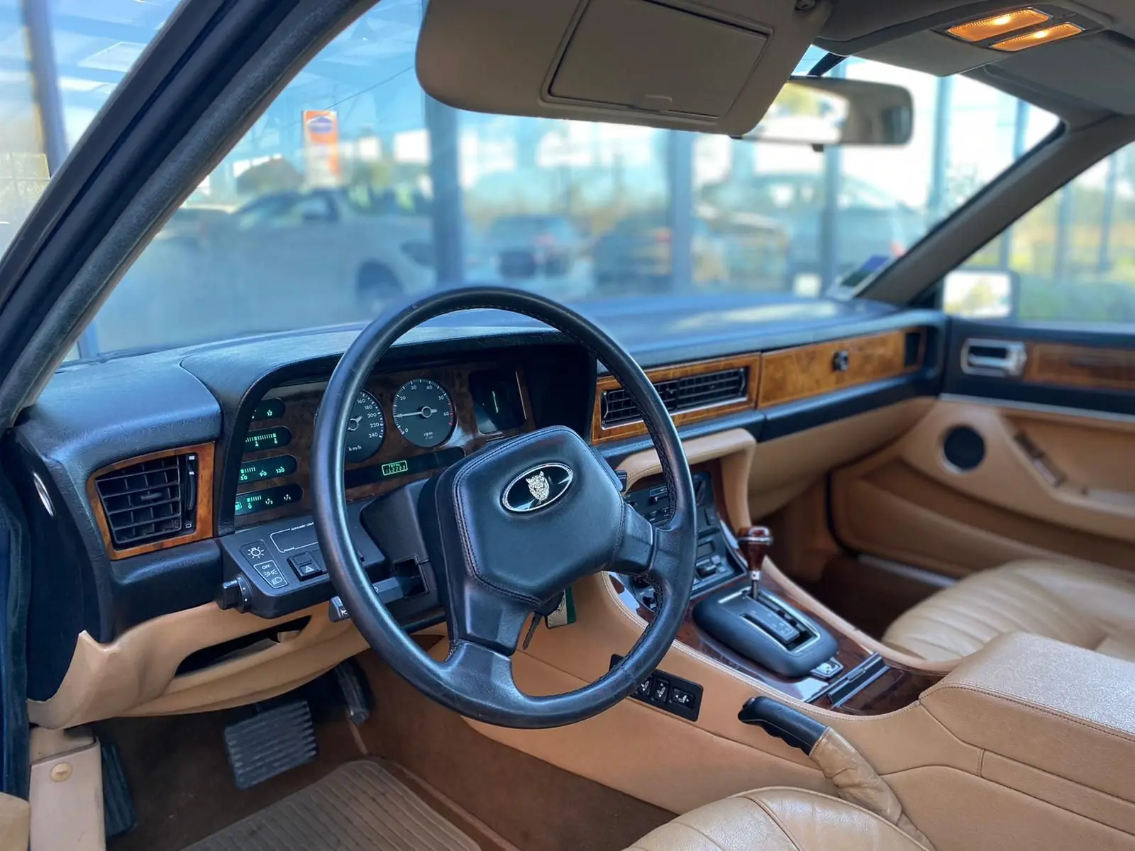 Intérieur beige et bois d'une Jaguar XJ6 3.6 Sovereign 1987, vue côté conducteur sur le tableau de bord et volant noir.
