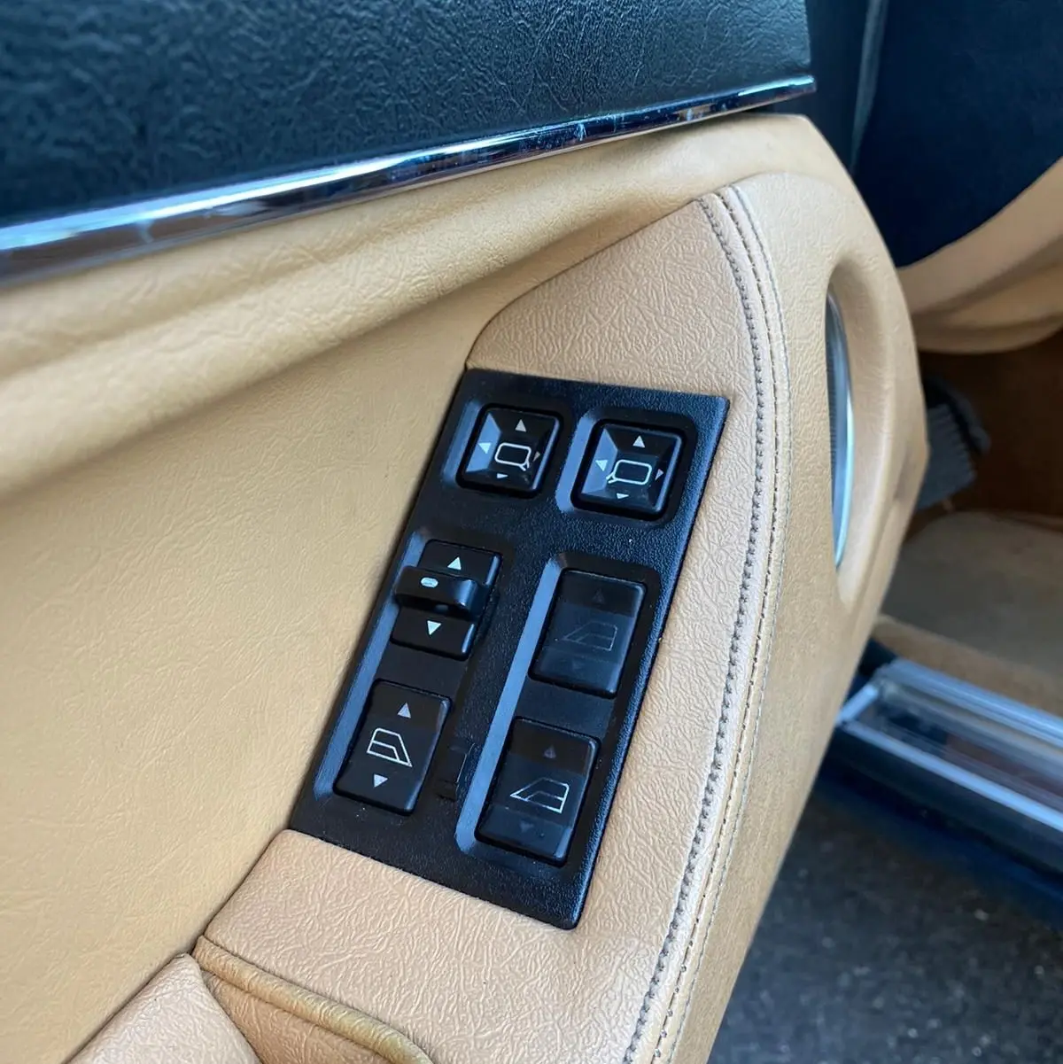 Gros plan sur les commandes électriques beige de la portière côté gauche d'une Jaguar XJ6 3.6 Sovereign bleue de 1987.