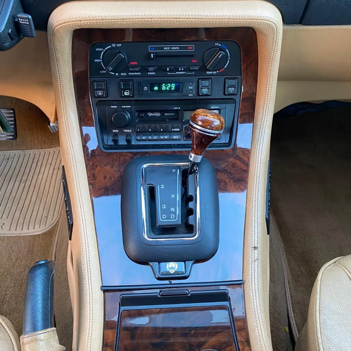 Gros plan sur la console centrale beige avec levier de vitesses boisée et tableau de bord en bois sur Jaguar XJ6 3.6 Sovereign 1987.