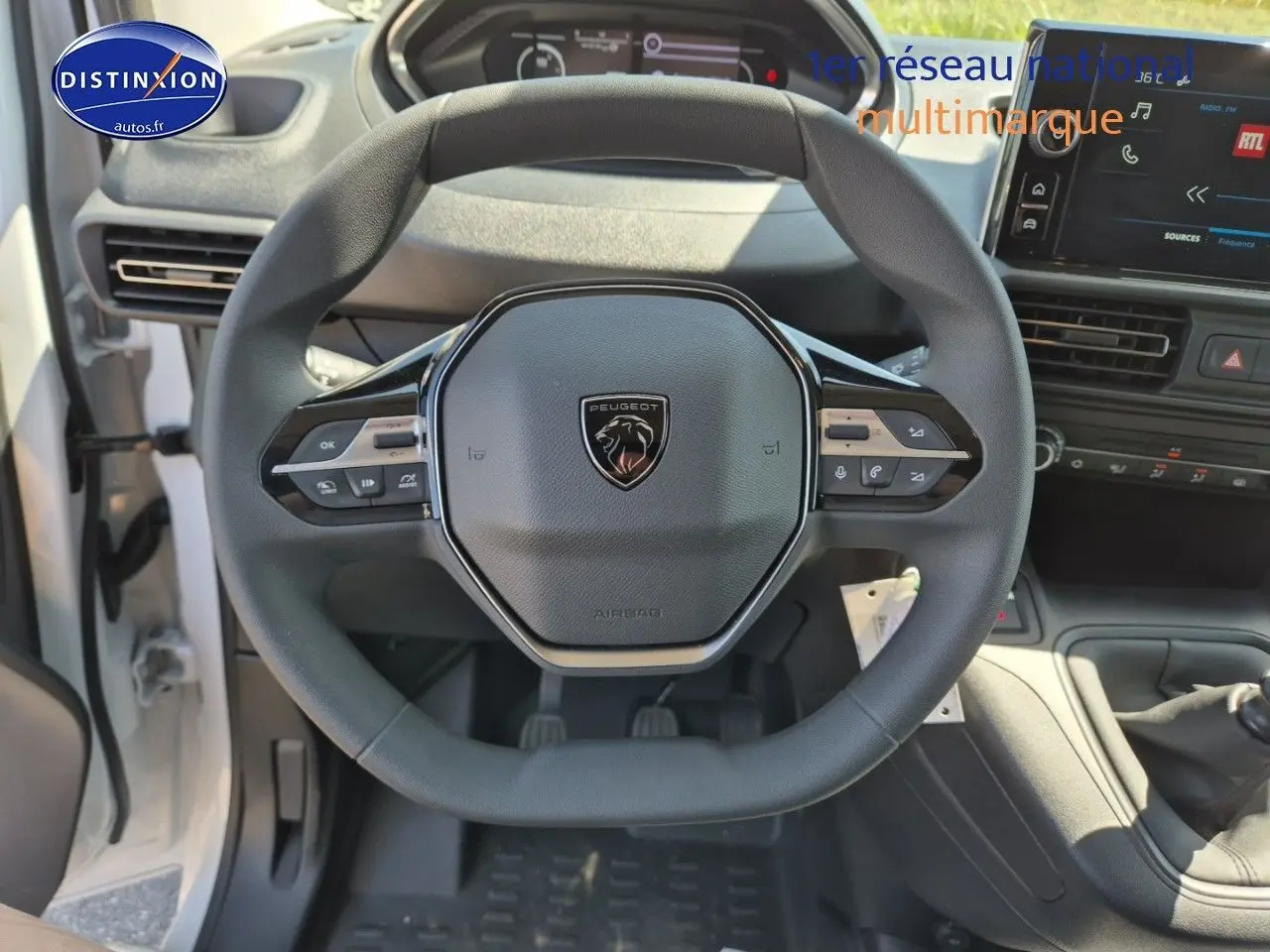 Vue plongeante sur le volant noir du Peugeot Partner 2025 avec tableau de bord et écran tactile visibles.