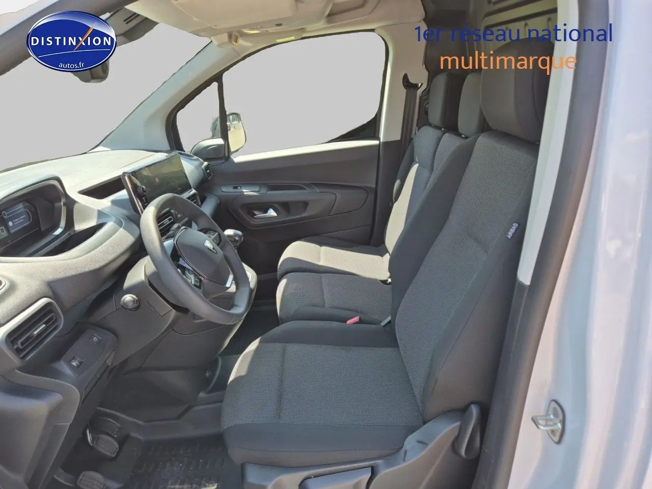 Intérieur du Peugeot Partner 2025 vu côté conducteur, sièges tissu gris et tableau de bord moderne noir.