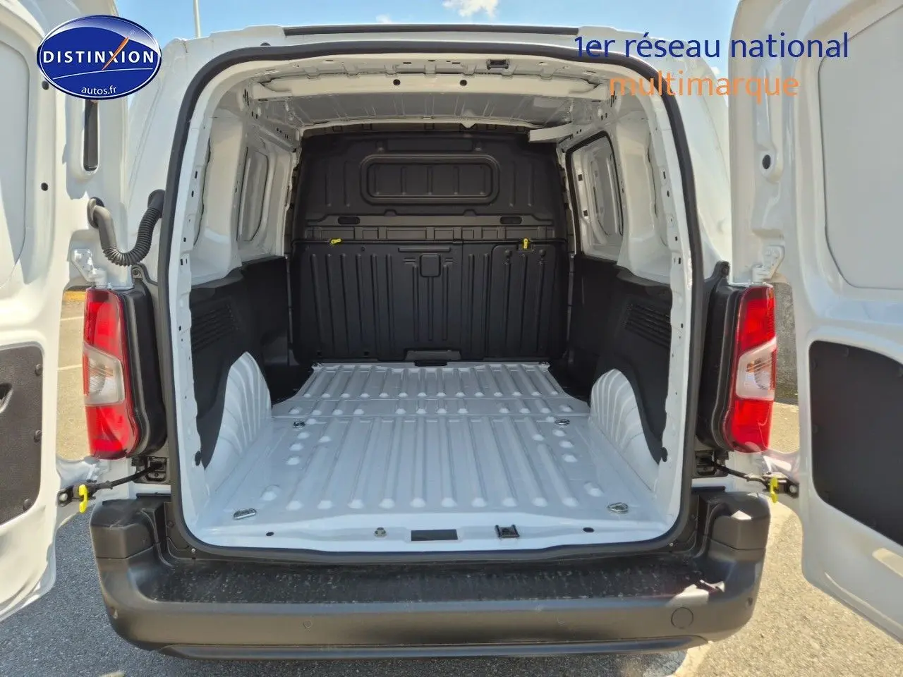 Vue arrière du Peugeot Partner 2025 blanc avec portes ouvertes montrant l'espace de chargement vide et la cloison noire.