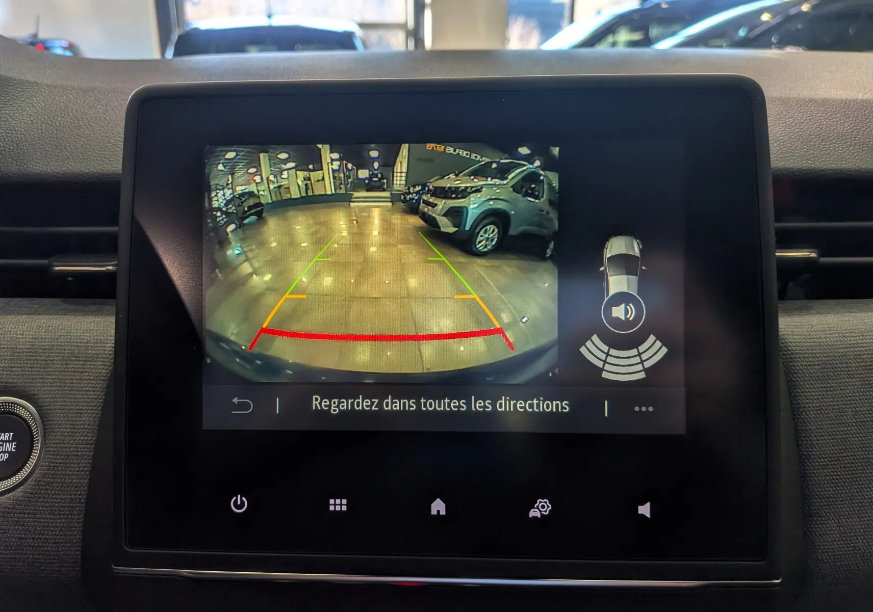 Écran central de la Renault Clio V Bleu Iron montrant la caméra de recul avec vue arrière en intérieur de garage.