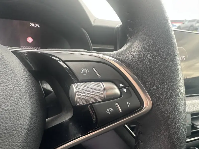 Gros plan sur les commandes multifonctions en aluminium brossé du volant cuir noir d'une Skoda Scala blanc cristal.