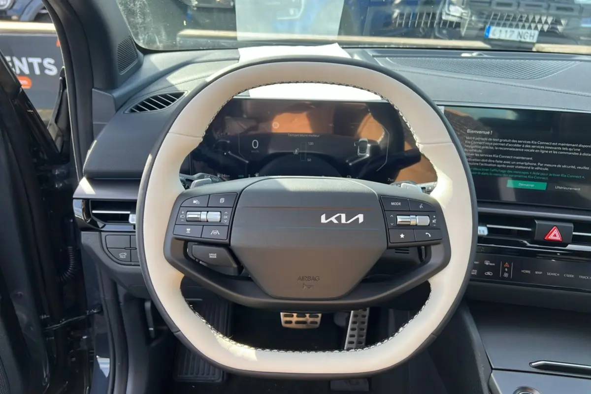 Vue intérieure centrée sur le volant cuir blanc et noir du Kia Sportage 2026 avec tableau de bord digital et écran tactile.