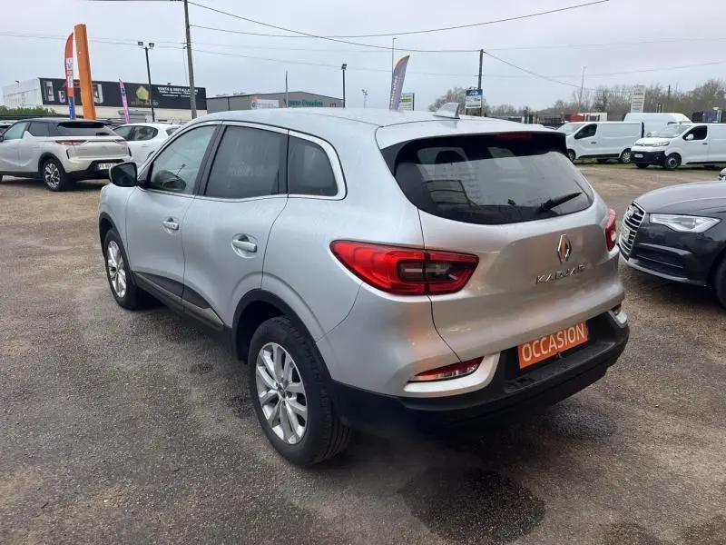 Vue 3/4 arrière droite d'un Renault Kadjar blanc glacier avec jantes alliage et feux arrière LED sur parking.