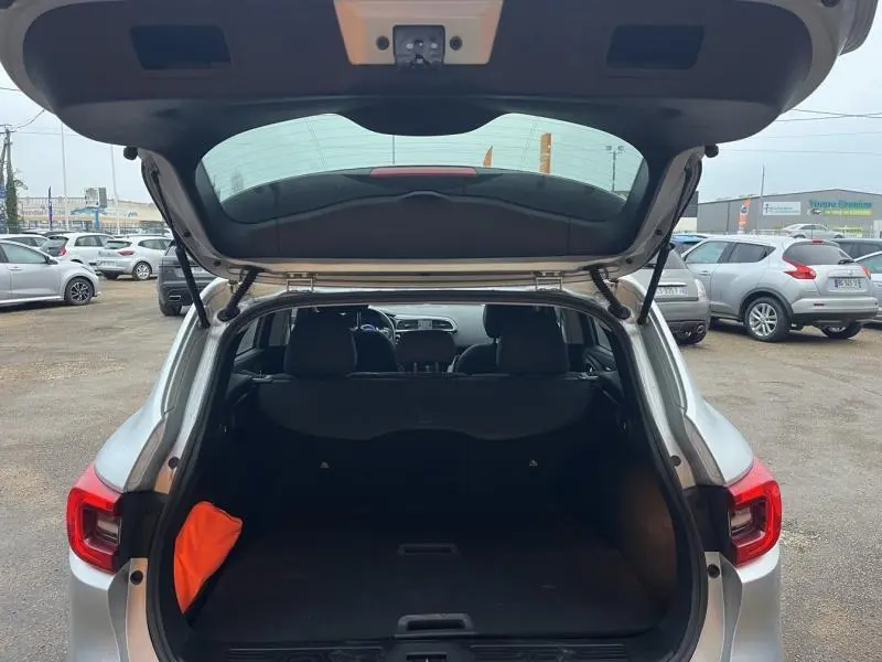 Coffre ouvert vu de l'arrière d'un Renault Kadjar blanc glacier 2022, intérieur noir avec un gilet orange visible.