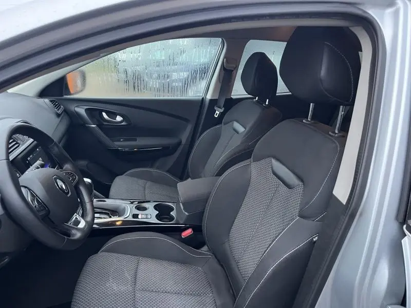 Intérieur avant du Renault Kadjar blanc 2022, sièges tissu carbone foncé et console centrale avec accoudoir et porte-gobelets.