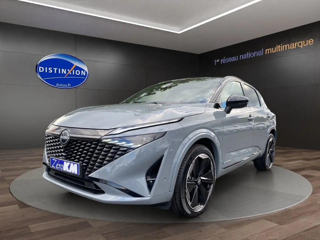 Nissan Qashqai 1.5 e-POWER 2025 gris ceramic et noir, vue 3/4 avant avec calandre noire distinctive et jantes stylées.