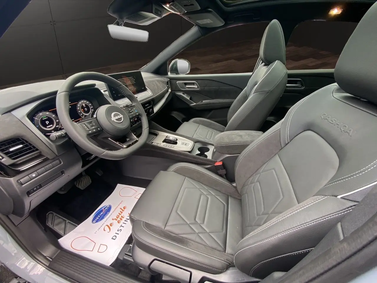 Intérieur du Nissan Qashqai 2025 en gris noir, vue côté conducteur, sièges cuir avec logo Qashqai brodé.
