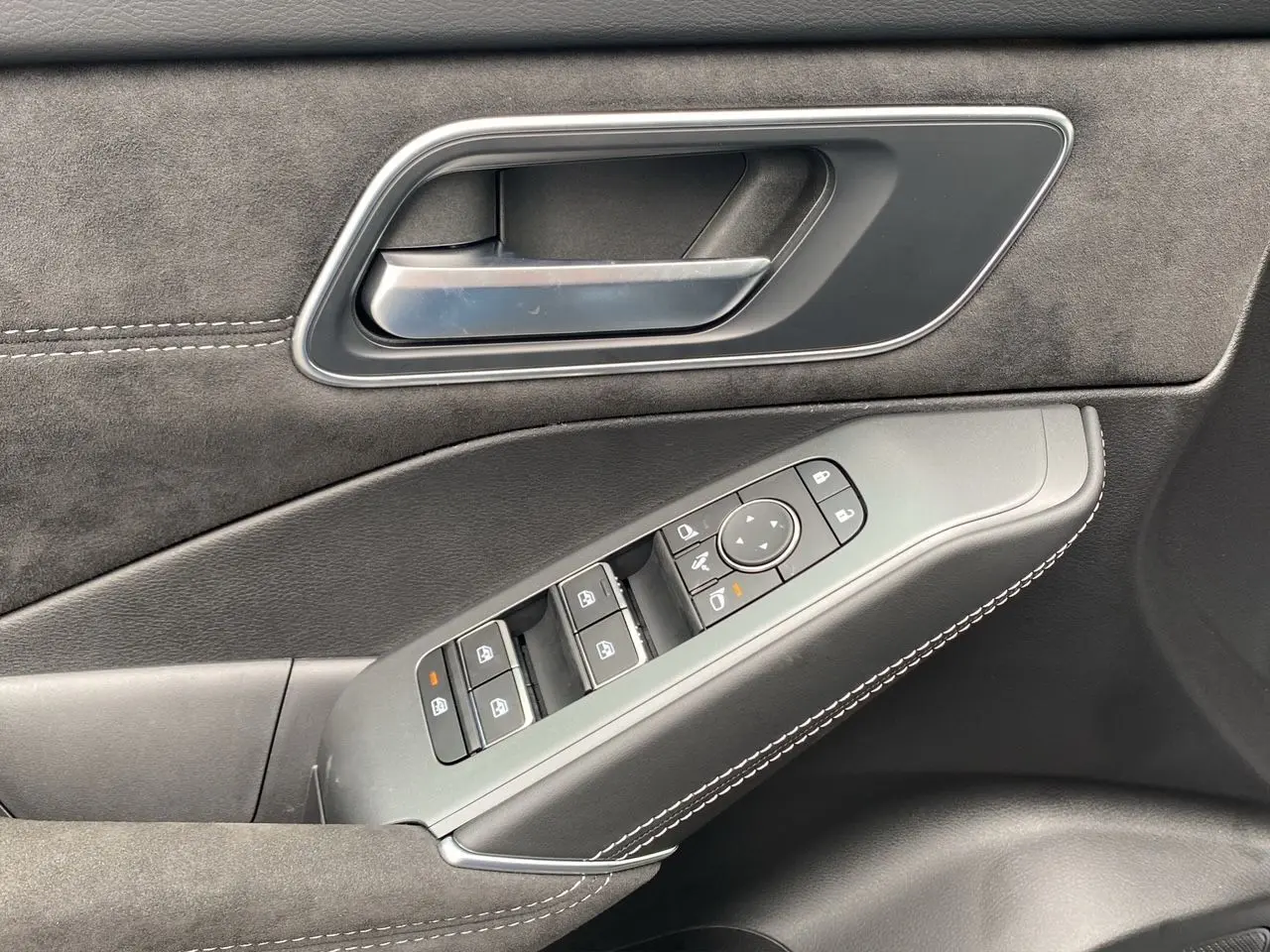 Gros plan sur la poignée intérieure et les commandes des vitres côté conducteur du Nissan Qashqai 2025 finition N-Design noir.