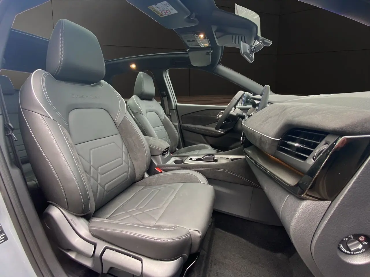 Vue intérieure côté conducteur du Nissan Qashqai 2025 avec sièges cuir gris et tableau de bord moderne.