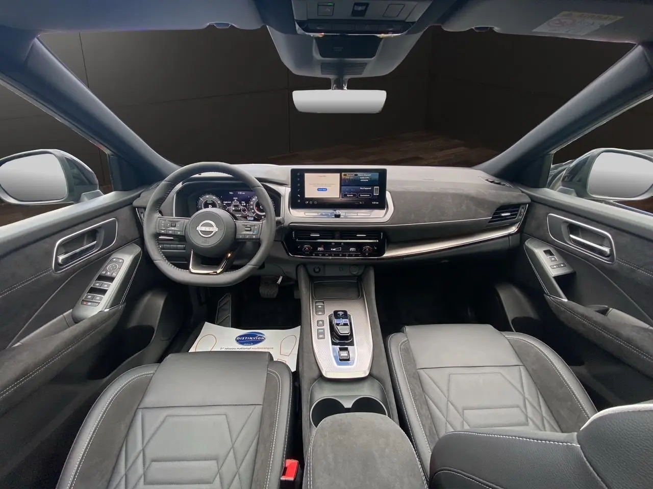 Vue intérieure avant du Nissan Qashqai 1.5 e-POWER 2025 avec tableau de bord numérique et sellerie cuir noir.