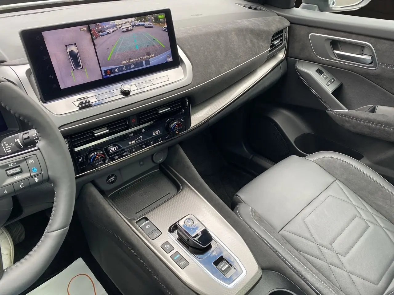 Vue intérieure côté passager du tableau de bord et console centrale du Nissan Qashqai 1.5 e-POWER 2025 en gris et noir avec écran tactile.