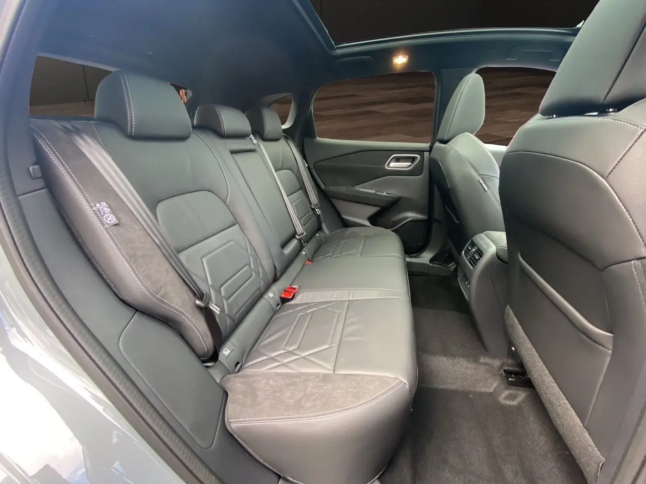 Vue intérieure côté droit des sièges arrière en cuir noir du Nissan Qashqai 1.5 e-POWER 2025 avec toit panoramique.