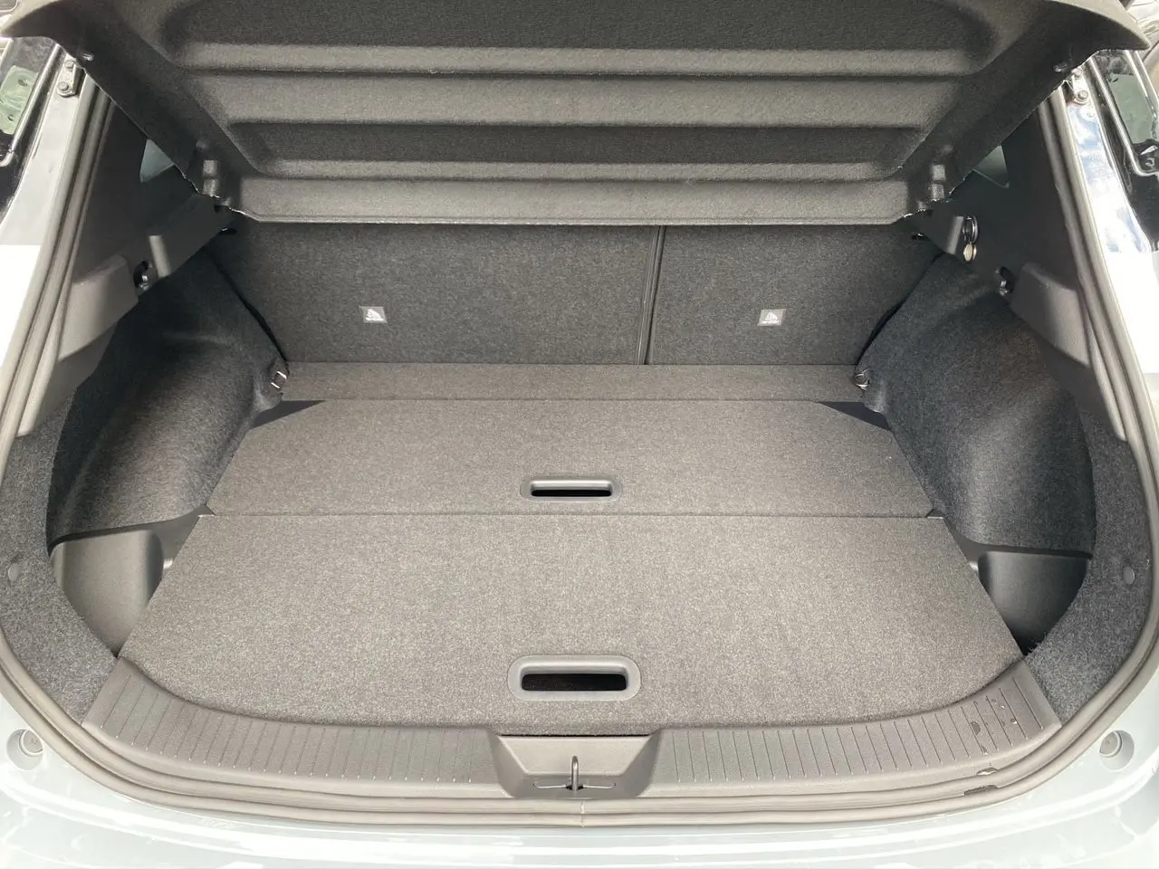 Coffre ouvert du Nissan Qashqai 2025 en gris ceramic et noir, montrant un espace de chargement plat et bien fini.